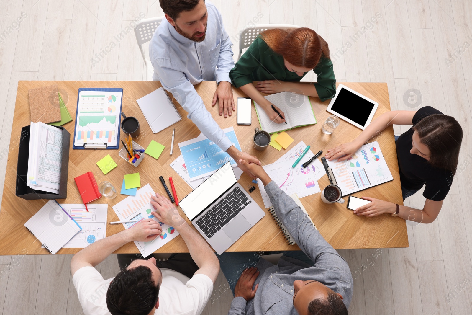 Photo of Team of employees working together at wooden table indoors, top view. Startup project