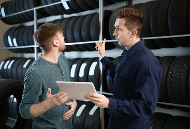 Service center consultant helping customer to choose tire in store