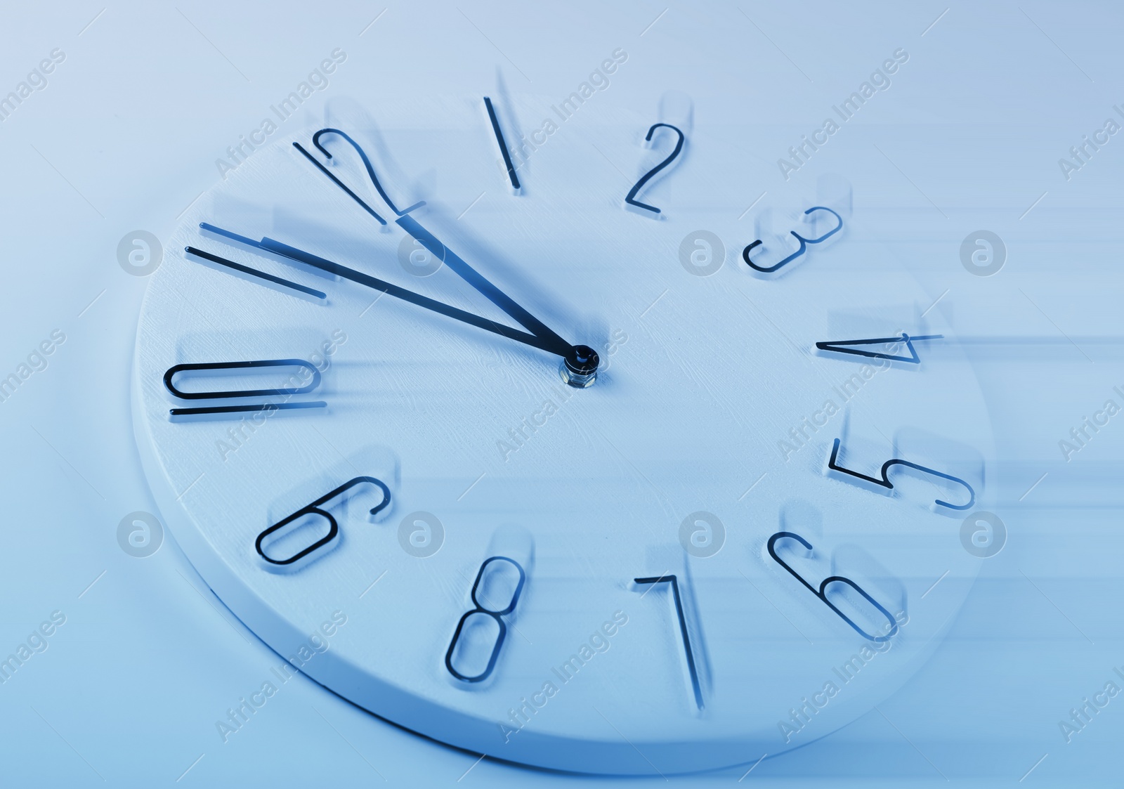 Image of Fleeting time concept. Clock on light blue background, motion effect