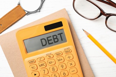 Calculator with word Debt on white wooden table, flat lay