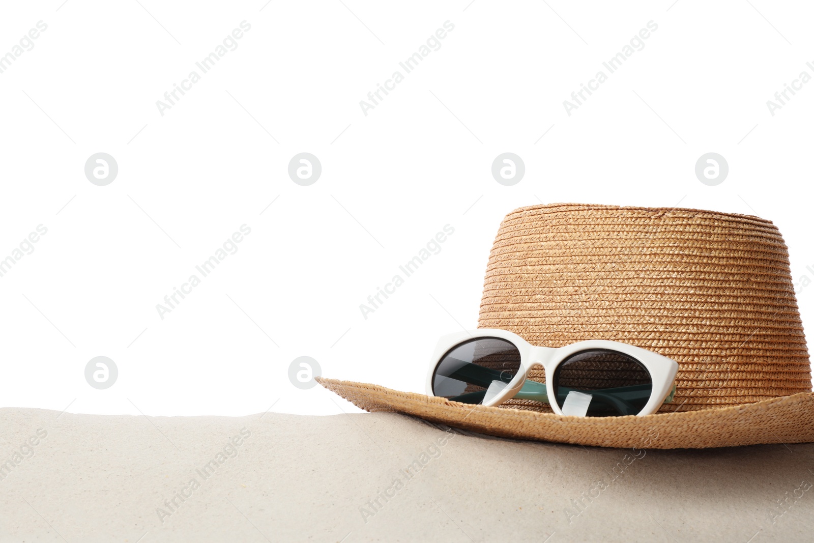 Photo of Hat and sunglasses on sand against white background, space for text. Stylish beach accessories