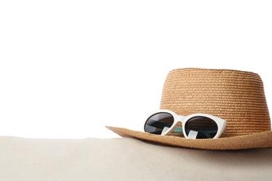 Photo of Hat and sunglasses on sand against white background, space for text. Stylish beach accessories