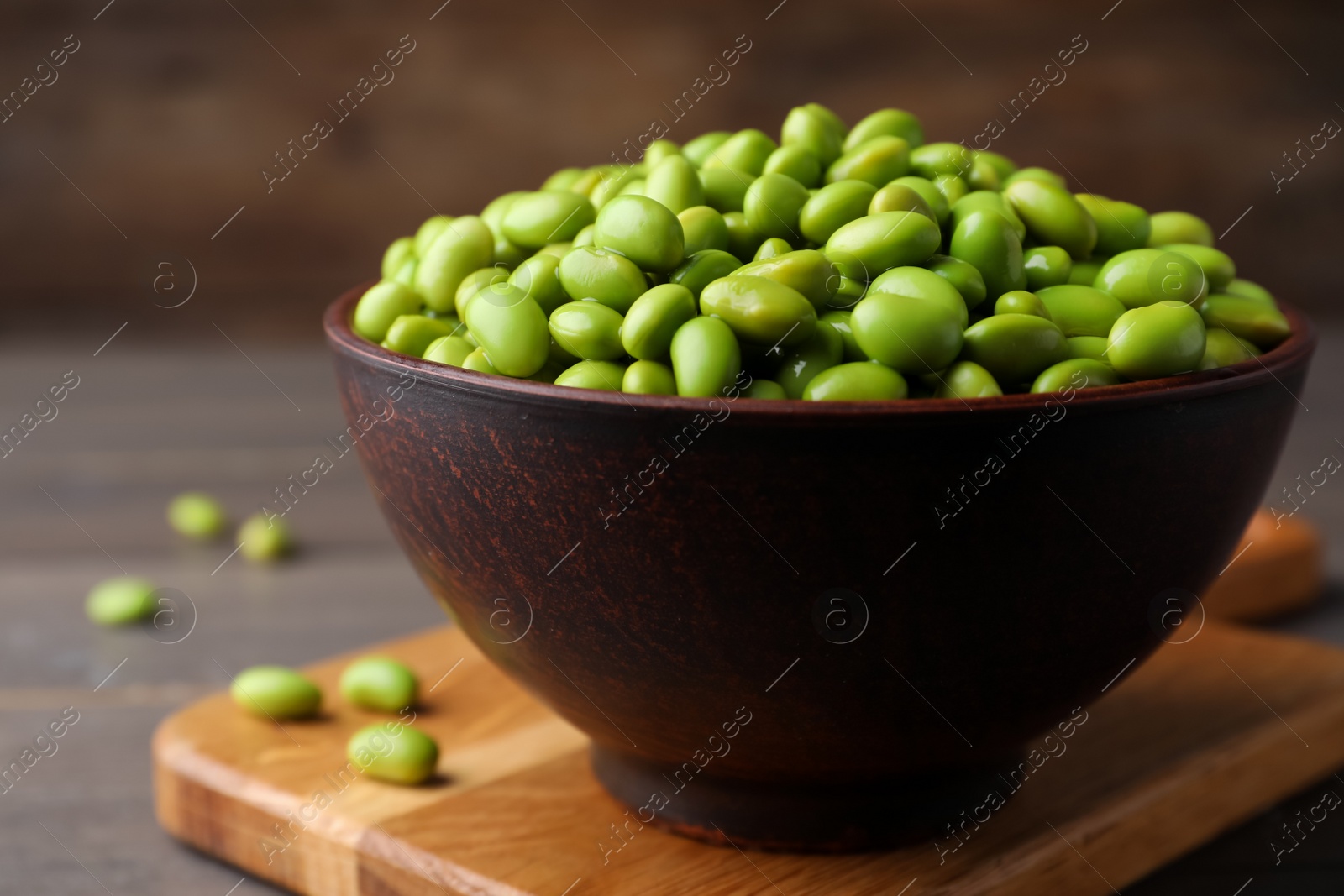 Photo of Bowl of delicious edamame beans on wooden table, closeup