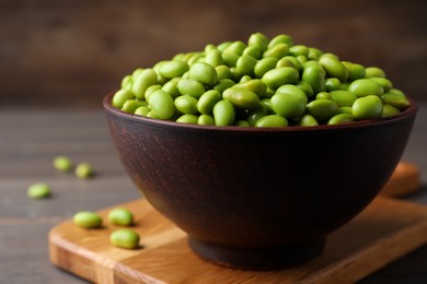 Photo of Bowl of delicious edamame beans on wooden table, closeup