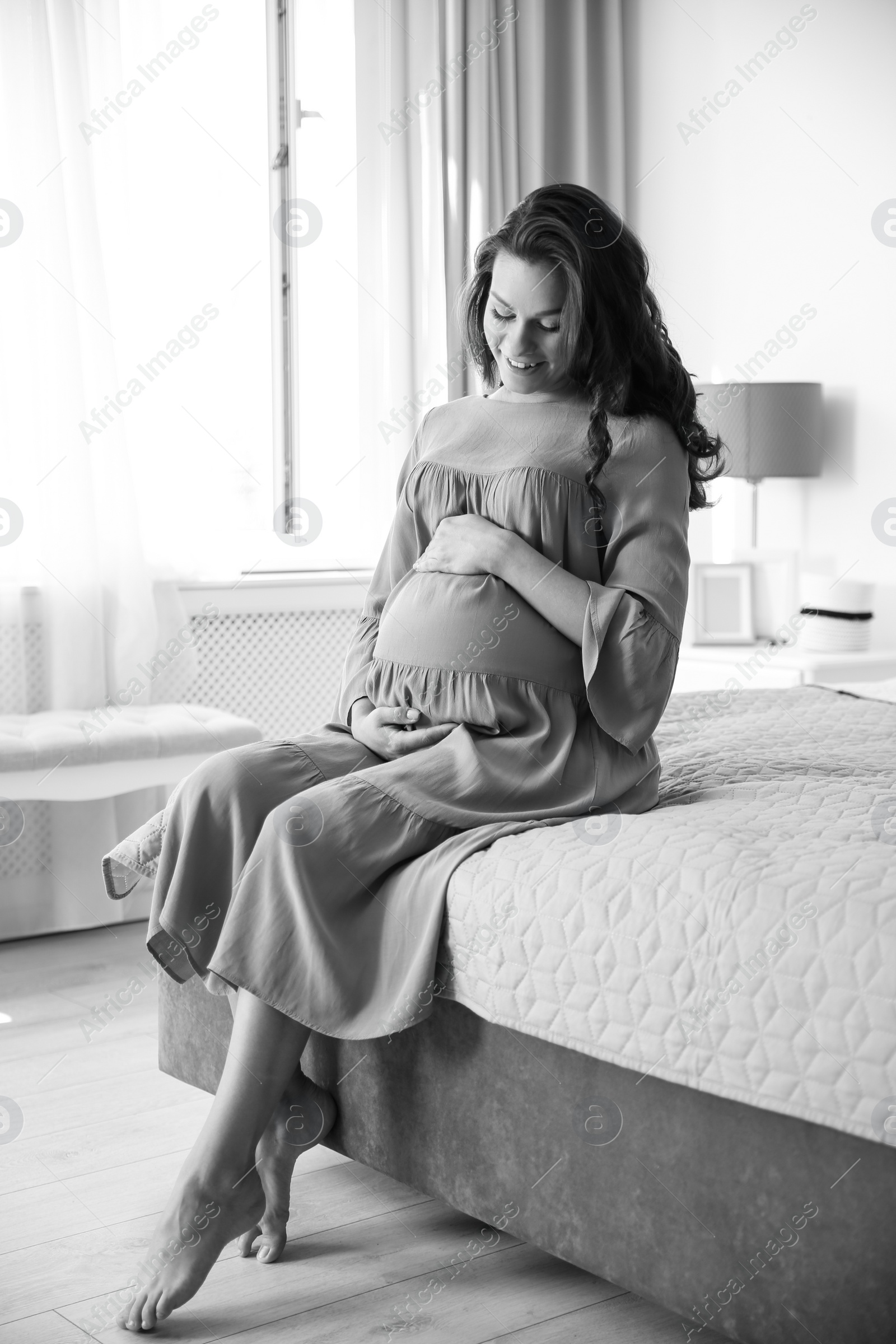 Photo of Young pregnant woman in bedroom, black and white effect