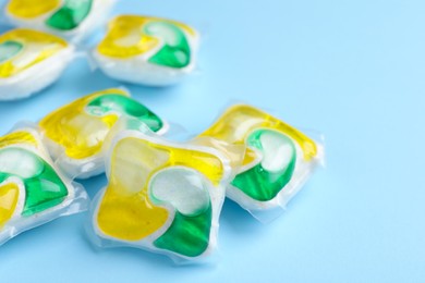 Photo of Many dishwasher detergent pods on light blue background