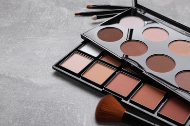Photo of Contouring palettes and brush on light gray background, closeup. Professional cosmetic product