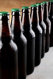Many bottles of beer on grey table against light brown background, closeup
