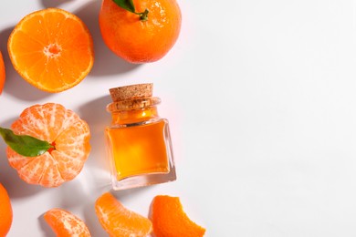 Photo of Aromatic tangerine essential oil in bottle and citrus fruits on white table, flat lay. Space for text