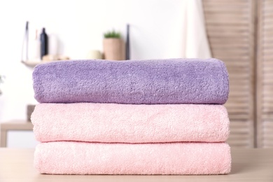 Photo of Stack of fresh towels on table in bathroom