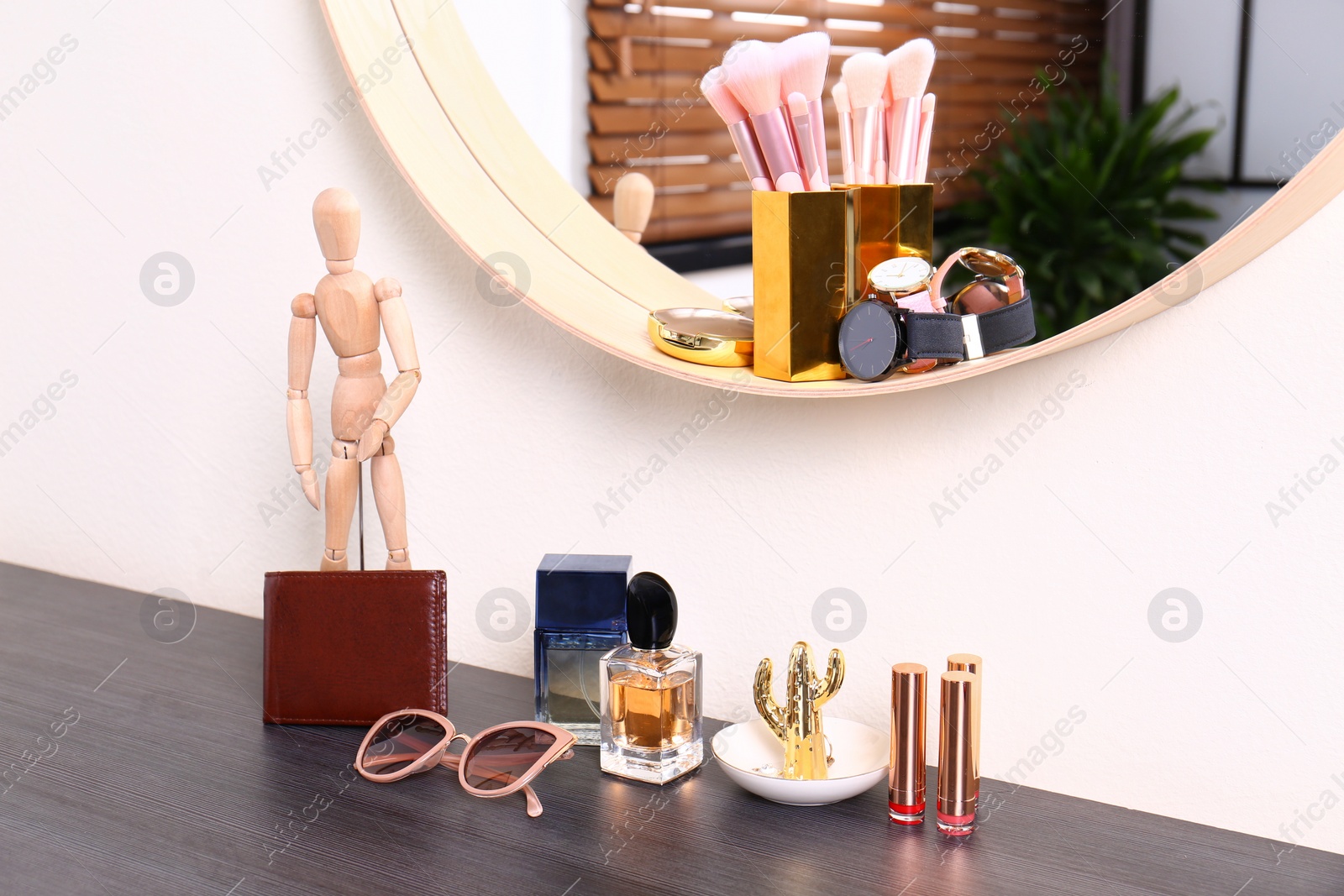 Photo of Stylish round mirror and dressing table with female accessories indoors. Interior design