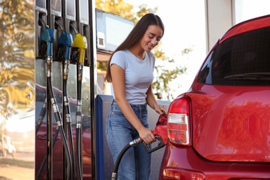 Photo of Young woman refueling car at self service gas station