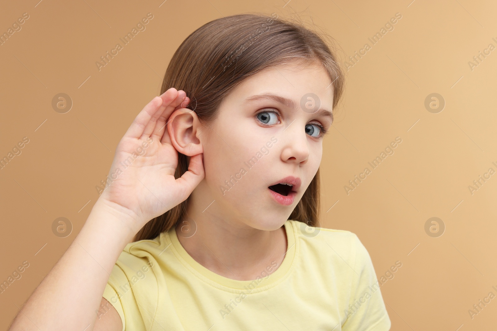 Photo of Little girl with hearing problem on pale brown background