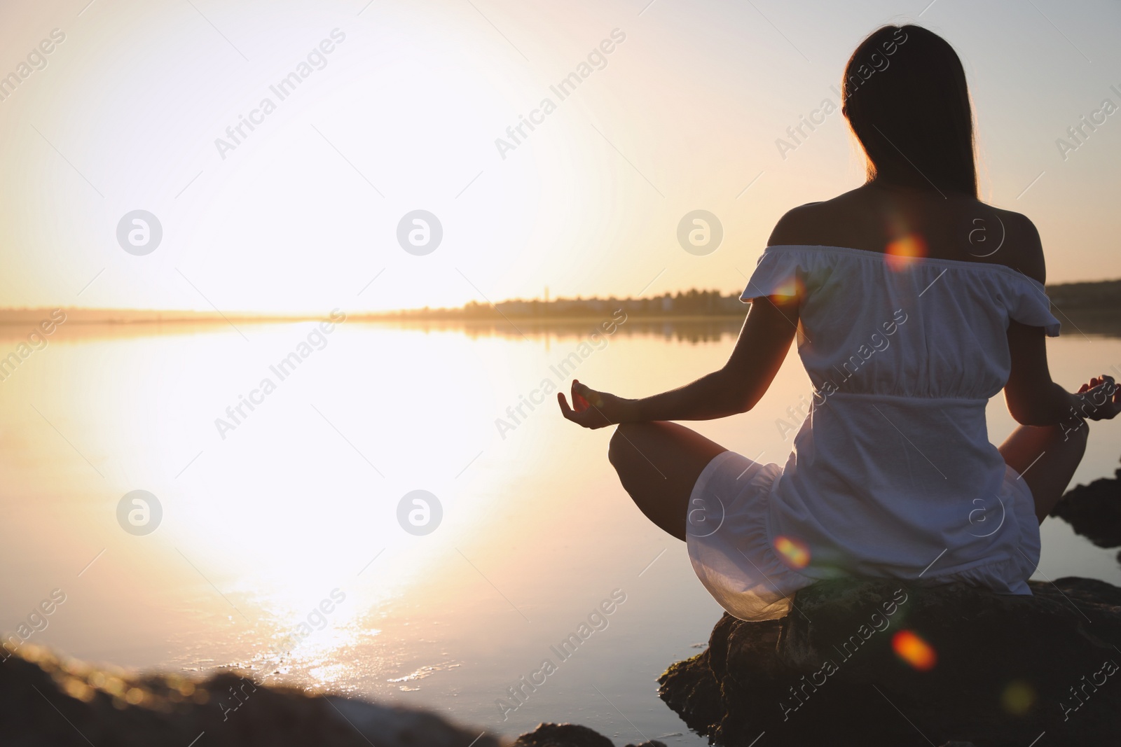 Photo of Woman practicing yoga near river on sunset. Healing concept