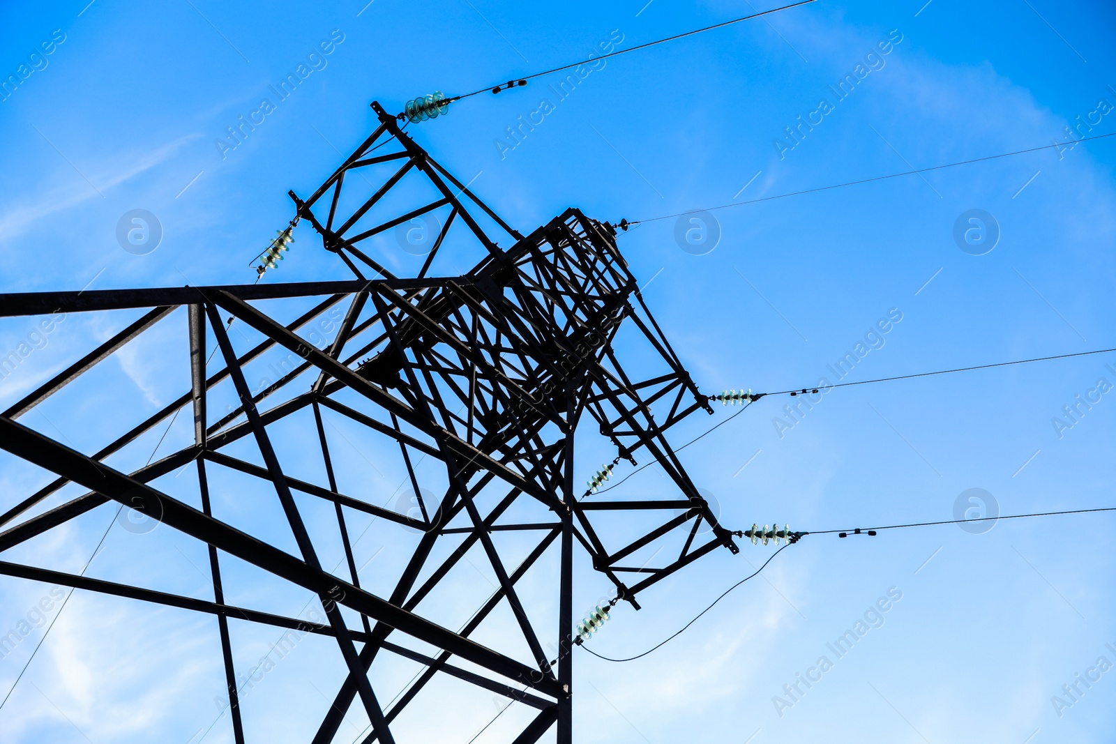 Photo of High voltage tower against beautiful blue sky, low angle view