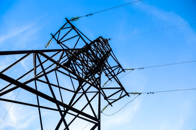Photo of High voltage tower against beautiful blue sky, low angle view