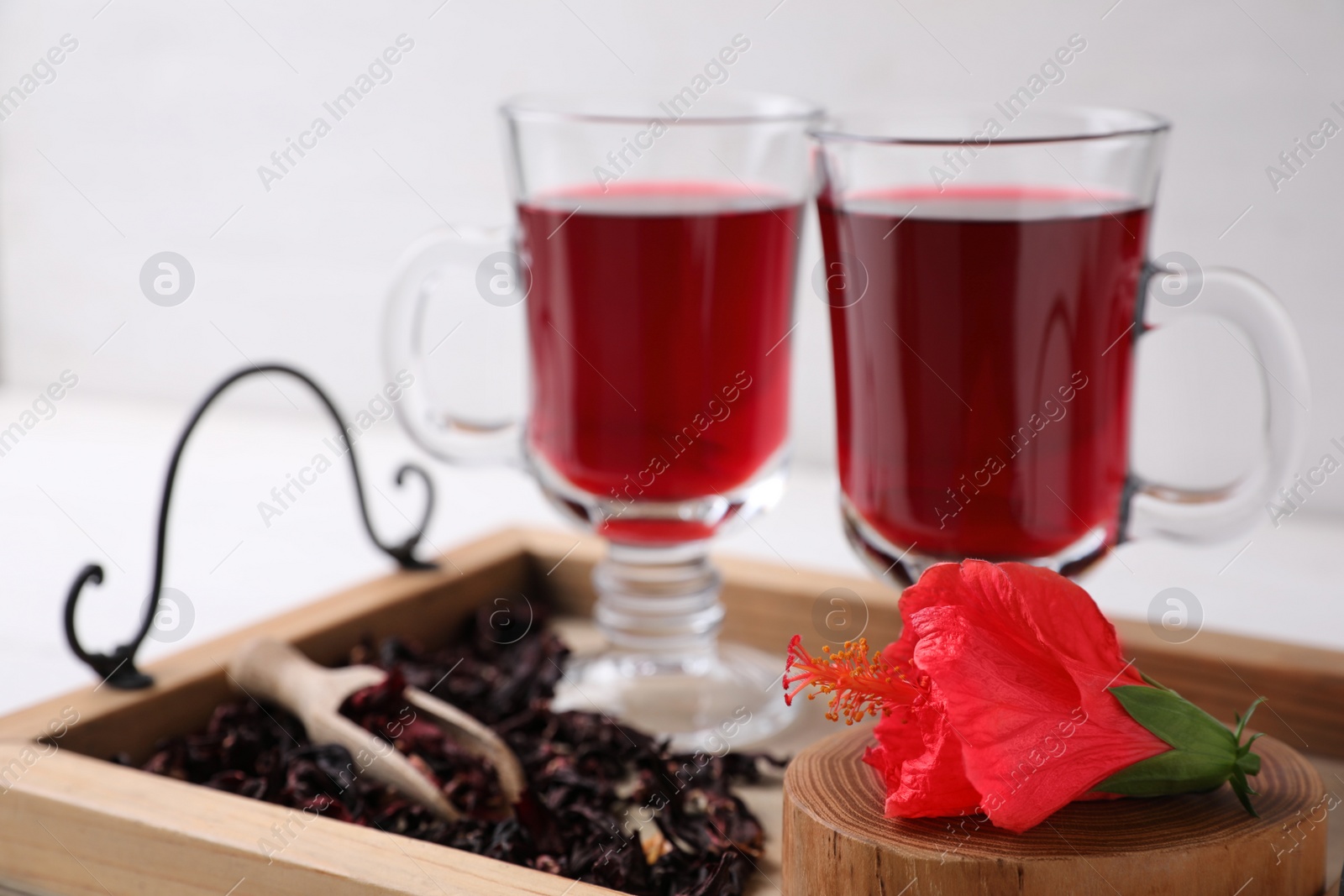 Photo of Beautiful Hibiscus flower and delicious tea on wooden tray, closeup