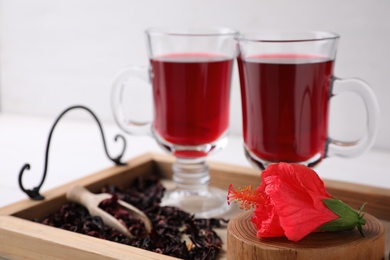 Photo of Beautiful Hibiscus flower and delicious tea on wooden tray, closeup