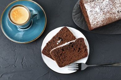 Tasty chocolate sponge cake with powdered sugar and coffee on black textured table, flat lay