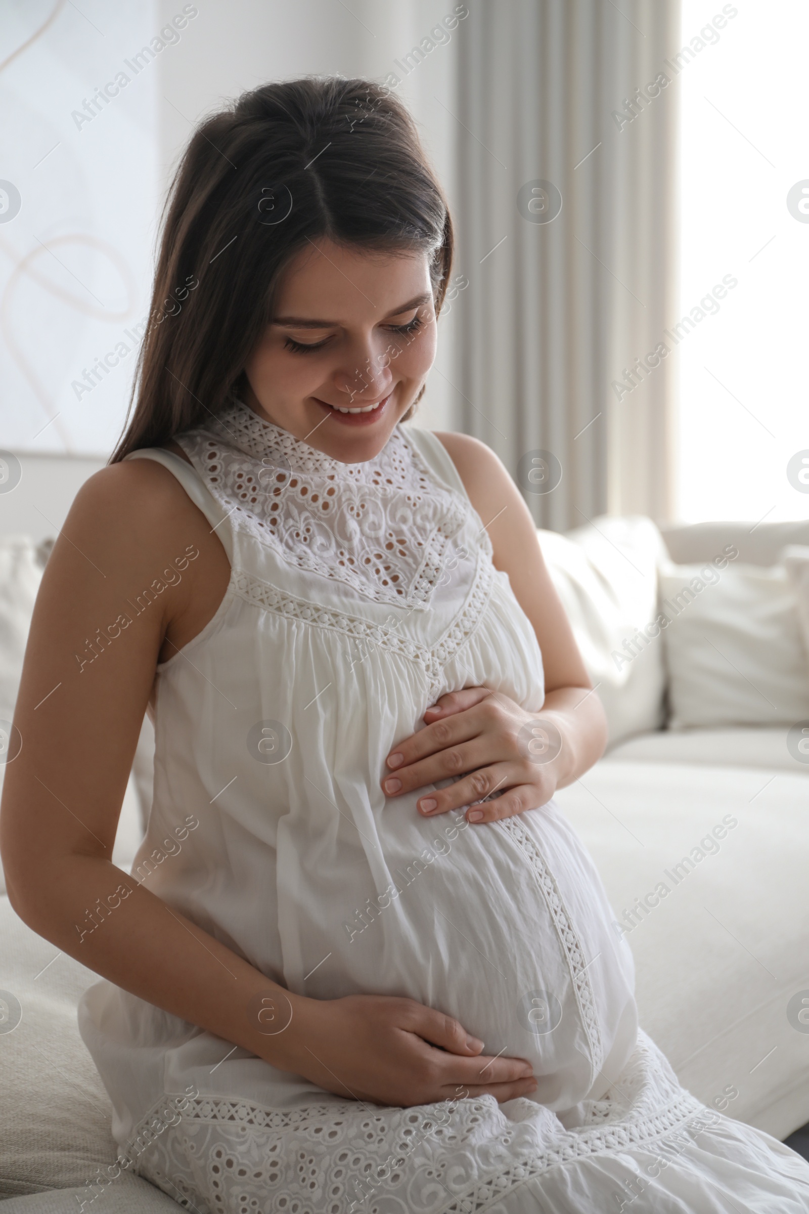 Photo of Pregnant young woman touching belly at home