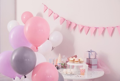 Photo of Party treats and items on table in room decorated with balloons