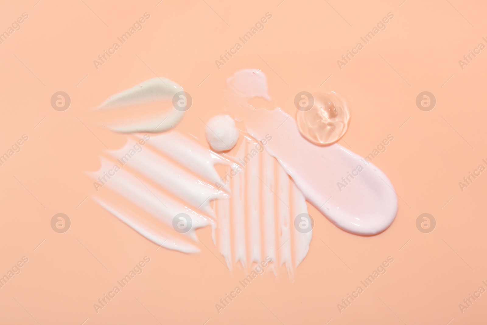 Photo of Samples of face cream on coral background, top view