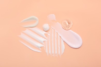 Photo of Samples of face cream on coral background, top view