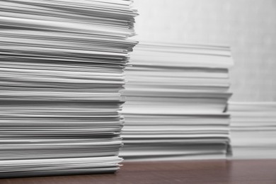 Stacks of white paper sheets on wooden table, space for text