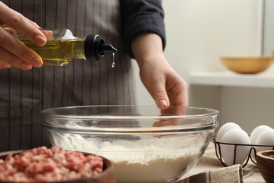 Woman making dough at wooden table, closeup