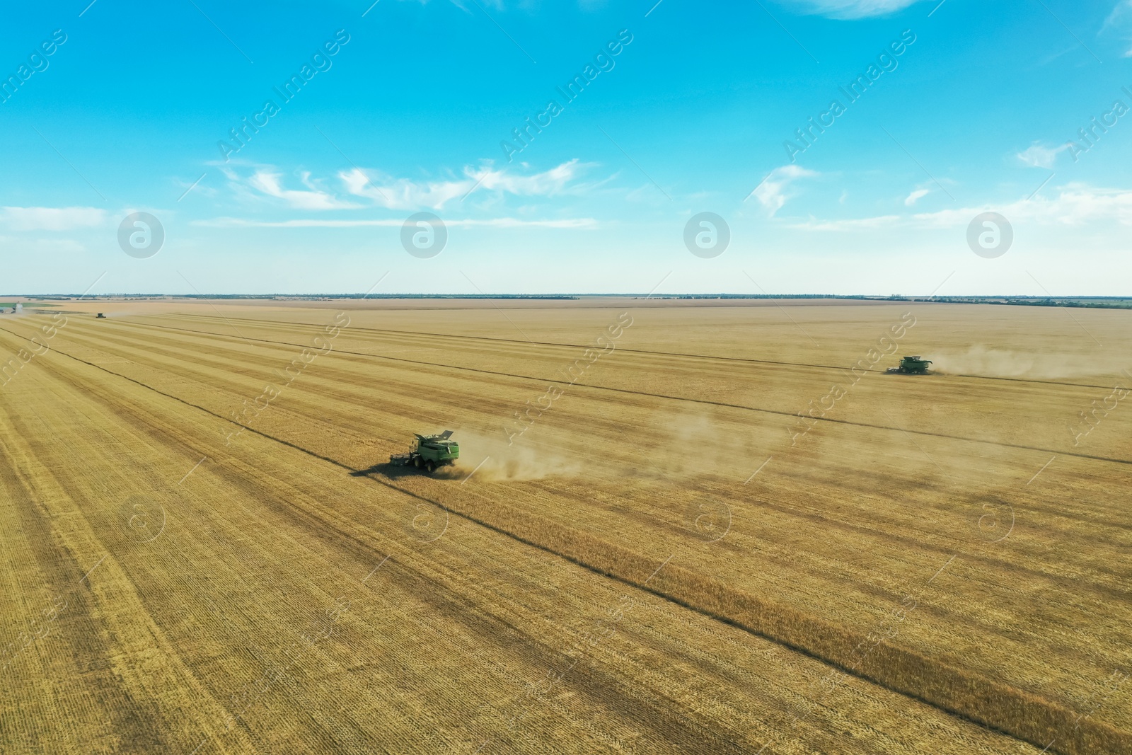 Photo of Beautiful aerial view of modern combine harvester working in field on sunny day. Agriculture industry