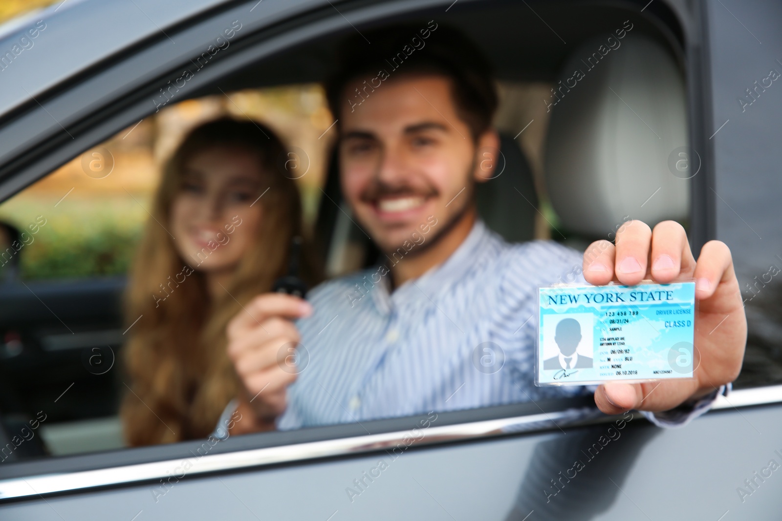 Photo of Young man holding driving license in car with passenger. Space for text