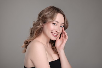 Portrait of smiling woman with curly hair on grey background