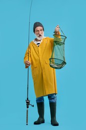 Fisherman holding rod and fishing net with catch on light blue background