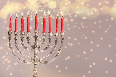 Image of Silver menorah with burning candles on light background, space for text. Hanukkah celebration