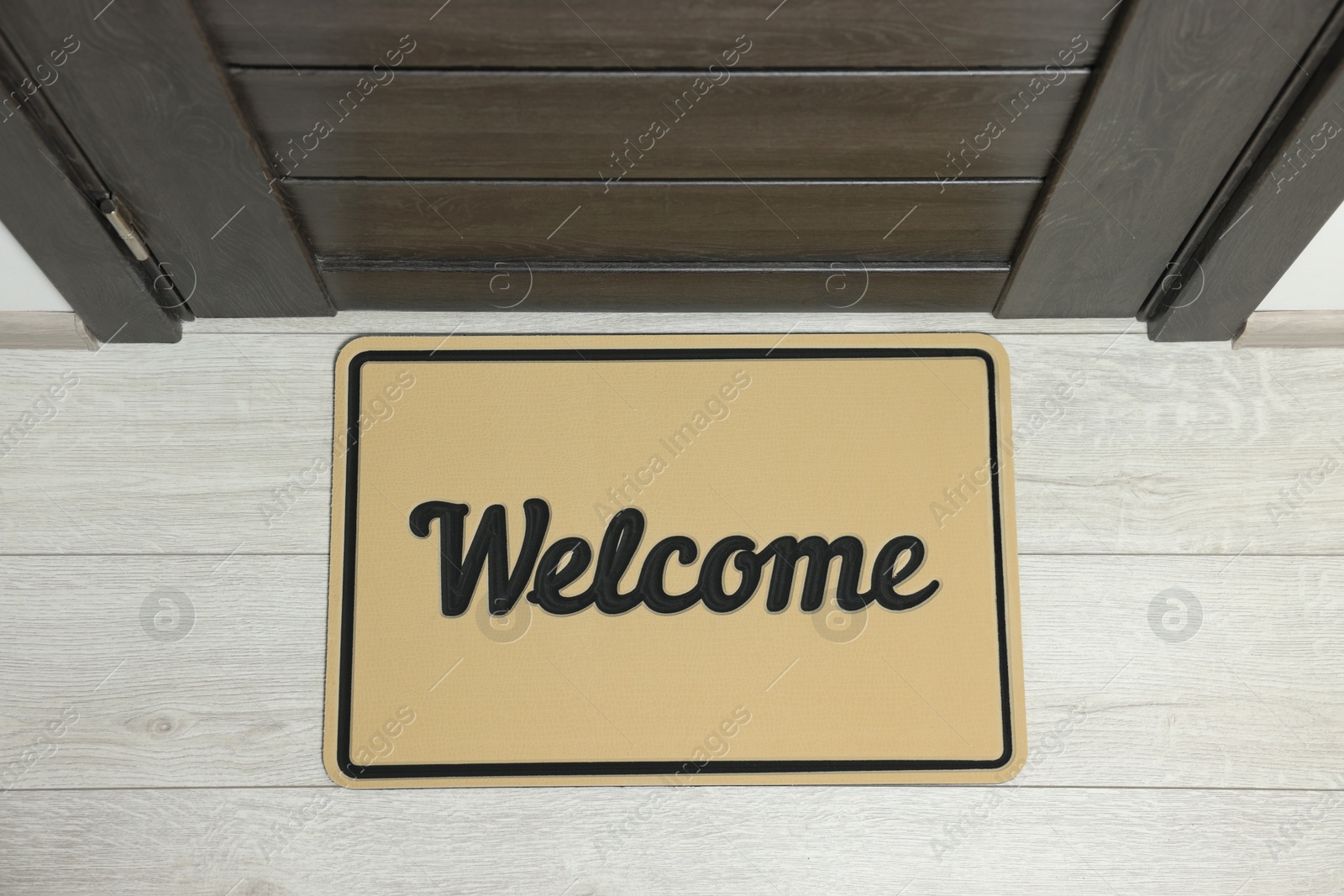 Photo of Beige doormat with word Welcome on white floor near entrance, top view