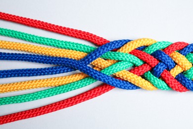 Photo of Braided colorful ropes isolated on white, top view. Unity concept