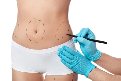 Photo of Doctor drawing marks on woman's body for cosmetic surgery operation against white background, closeup