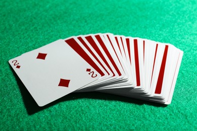 Photo of Playing cards and two of diamonds on green table