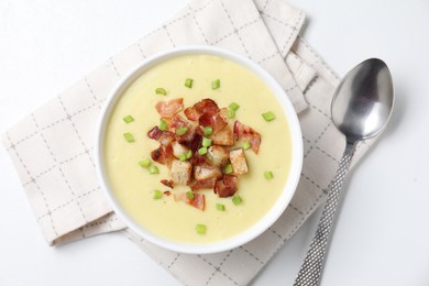 Photo of Tasty potato soup with bacon in bowl and spoon on white table, flat lay