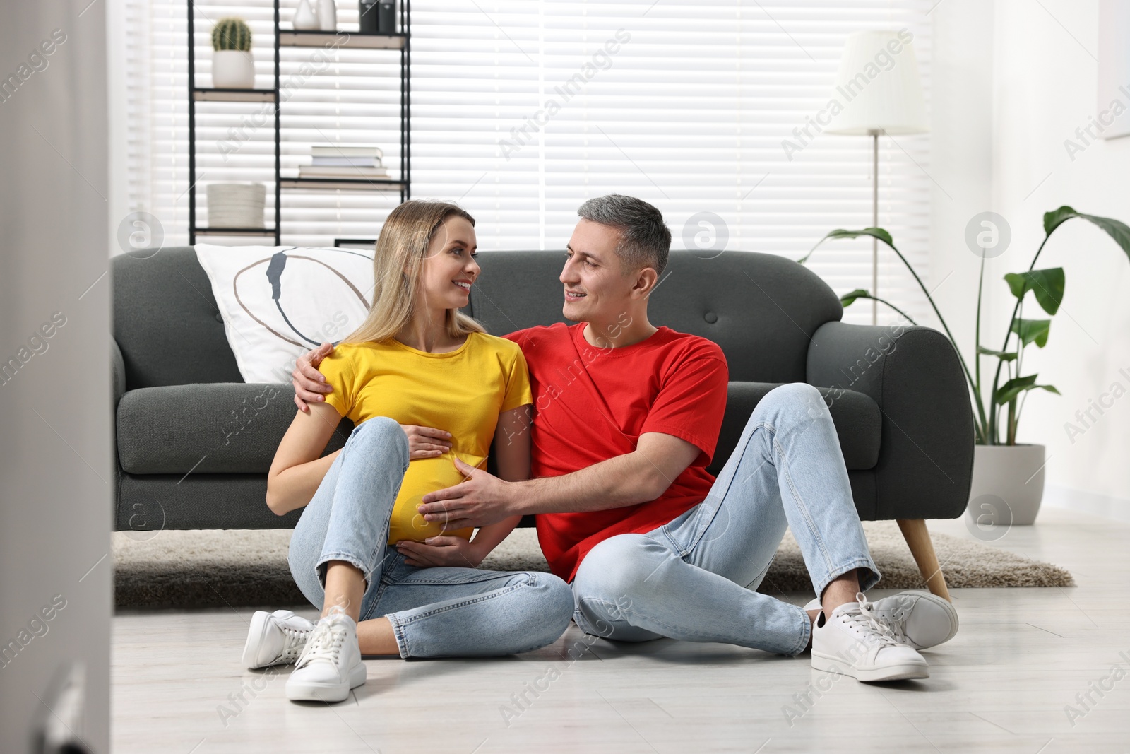 Photo of Young family housing concept. Pregnant woman with her husband on floor at home