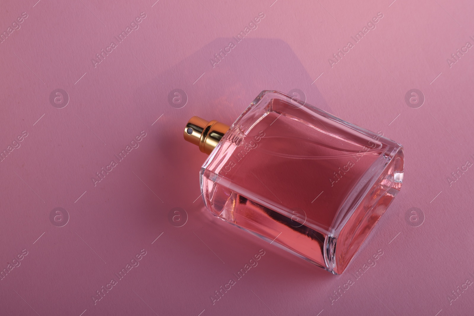 Photo of Luxury women's perfume in bottle on violet background