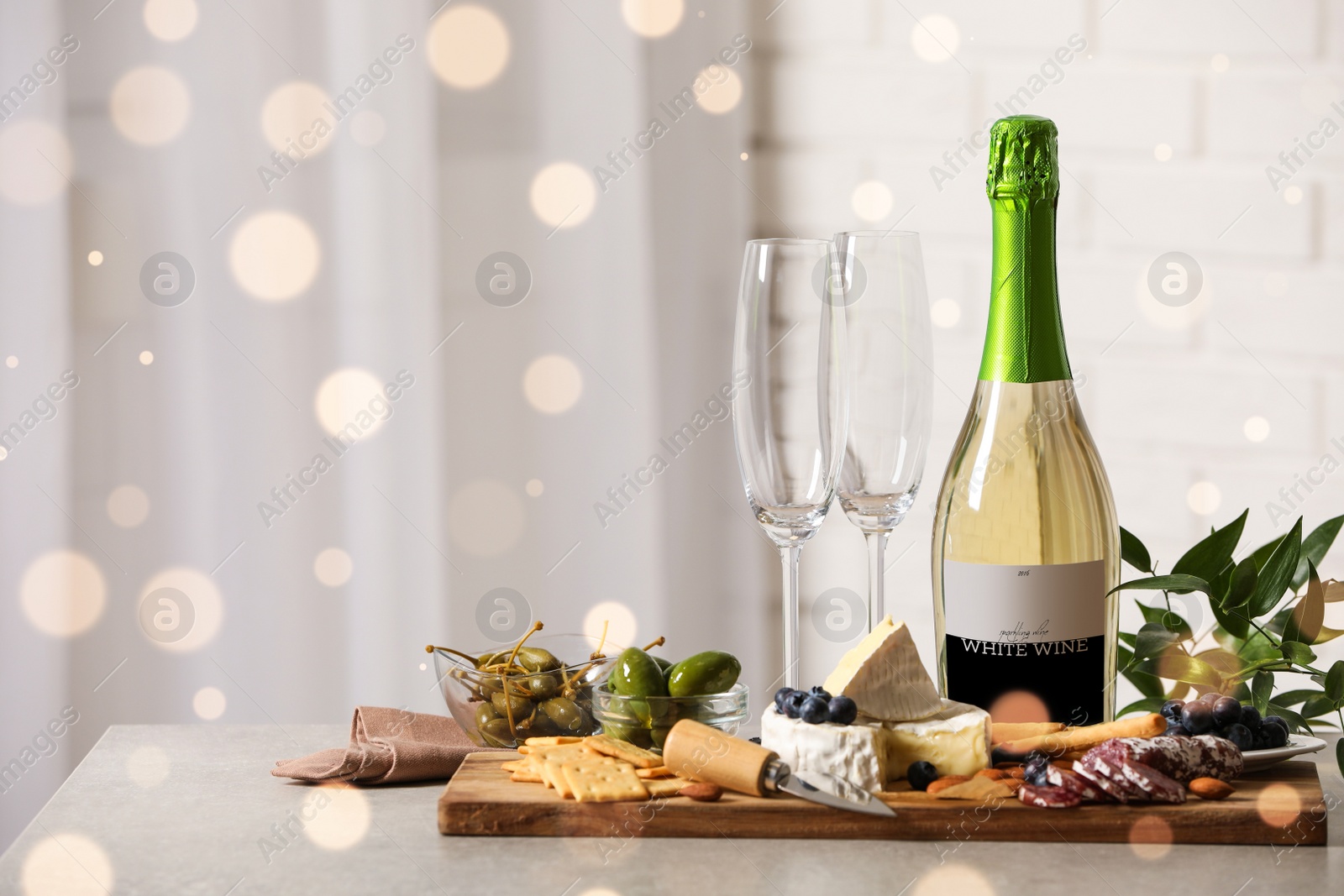 Photo of Bottle of sparkling wine, glasses and delicious snacks on grey table indoors. Space for text