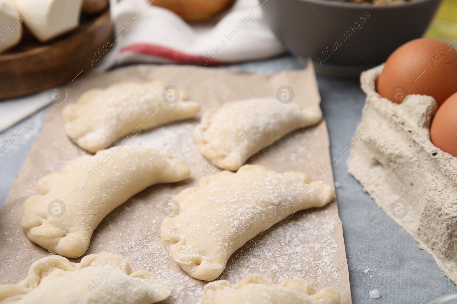 Photo of Raw dumplings (varenyky) with tasty filling on grey table, closeup. Traditional Ukrainian dish