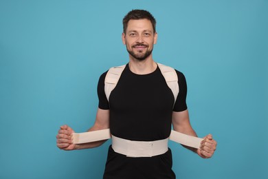 Photo of Handsome man with orthopedic corset on blue background