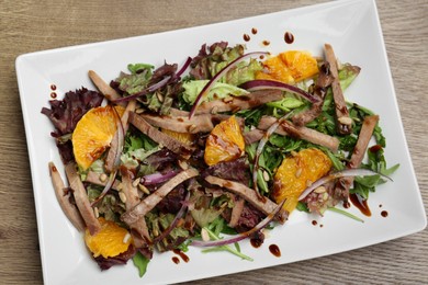 Delicious salad with beef tongue, orange and onion on wooden table, top view