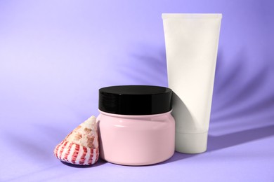 Photo of Tube of cream, hair mask and seashell on violet background