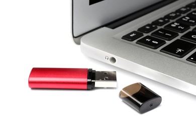 Photo of Usb flash drive near laptop on white background