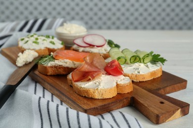 Photo of Toasted bread with cream cheese and different toppings on white wooden table