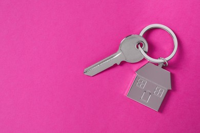 Photo of Key with keychain in shapehouse on pink background, top view. Space for text