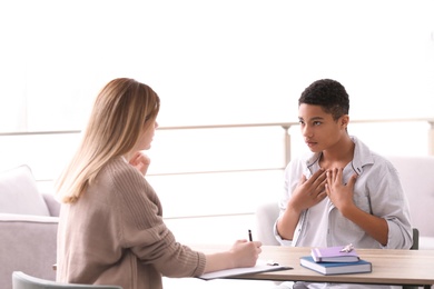 Photo of Young female psychologist working with teenage boy in office